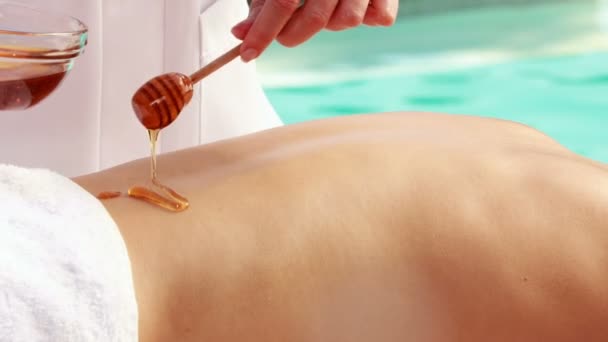 Beauty therapist pouring honey onto womans back — Stock Video