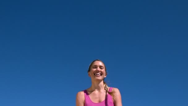 Fitte Blondine lächelt und springt an sonnigem Tag auf — Stockvideo