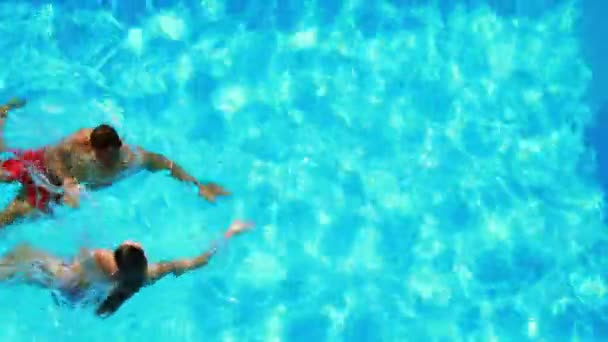 Happy couple swimming in clear blue pool — Stock Video