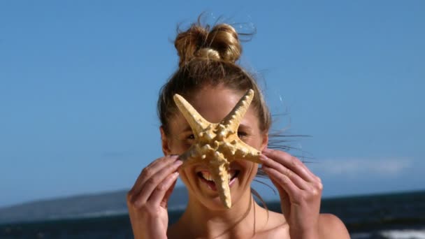 Leende blondin håller upp sjöstjärnor — Stockvideo