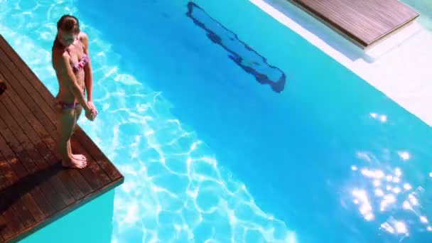 Brunetka nurkowanie w jasny niebieski basen — Wideo stockowe