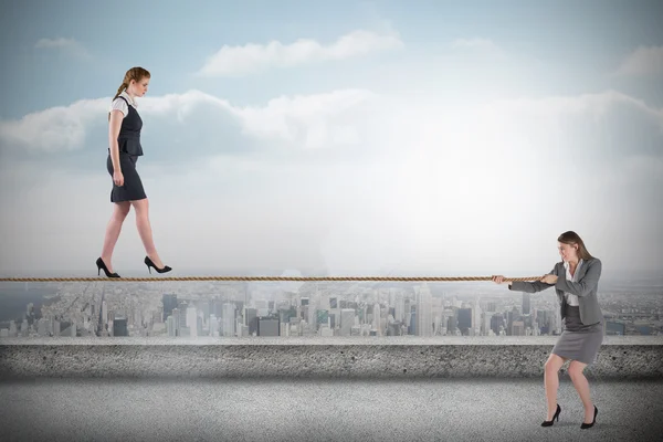 Young business woman pulling a tightrope for businesswoman — Stock Photo, Image