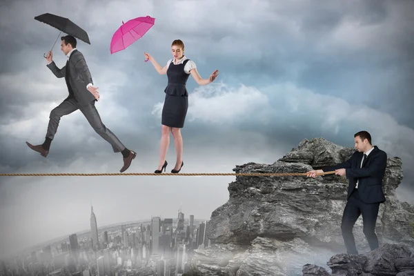 Young businessman pulling a tightrope for business people — Stock Photo, Image