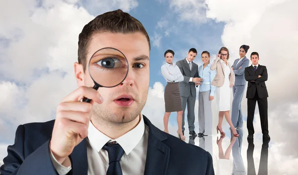 Businessman looking through magnifying glass — Stock Photo, Image