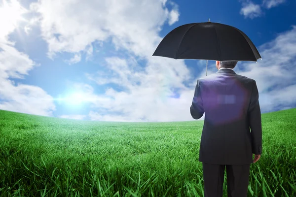 Mature businessman holding an umbrella — Stock Photo, Image