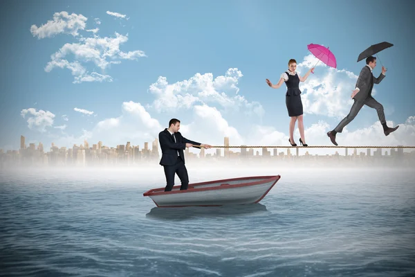 Young businessman pulling a tightrope for business people — Stock Photo, Image