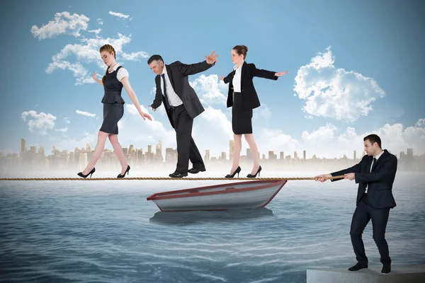 Young businessman pulling a tightrope for business people — Stock Photo, Image