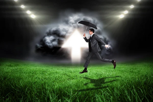 Businessman jumping holding an umbrella — Stock Photo, Image