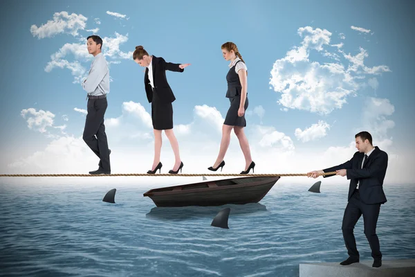 Young businessman pulling a tightrope for business people — Stock Photo, Image