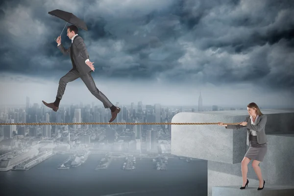 Young businesswoman pulling a tightrope for businessman — Stock Photo, Image