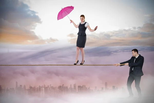 Young businessman pulling a tightrope for businesswoman — Stock Photo, Image