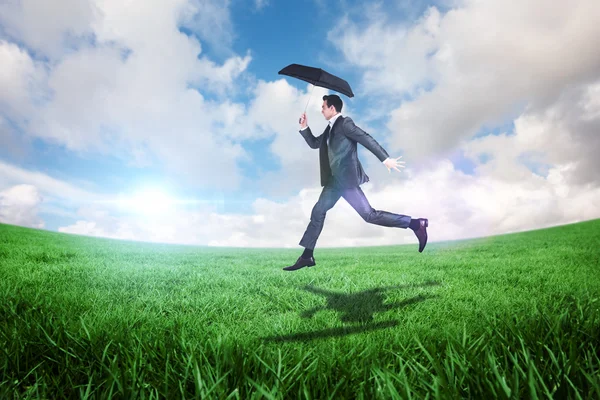 Businessman jumping holding an umbrella — Stock Photo, Image