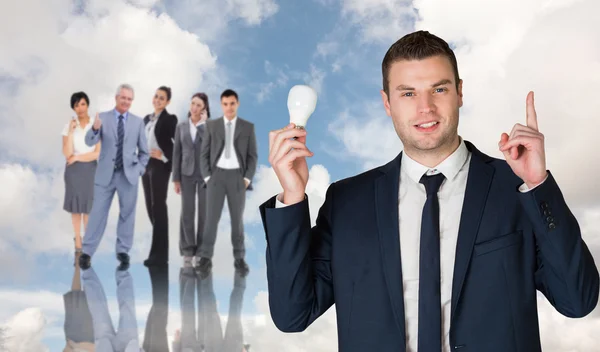 Businessman holding light bulb and pointing — Stock Photo, Image