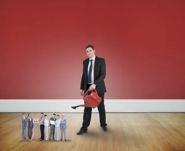 Businessman watering tiny business team — Stock Photo, Image