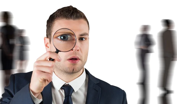 Businessman looking through magnifying glass — Stock Photo, Image