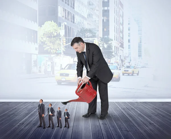 Businessman watering tiny businessman — Stock Photo, Image