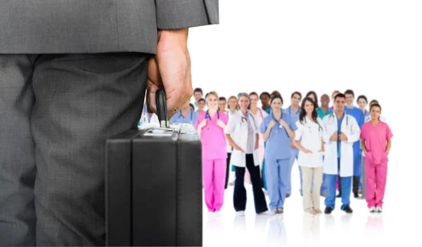 Businessman holding briefcase against group of workers — Stock Photo, Image