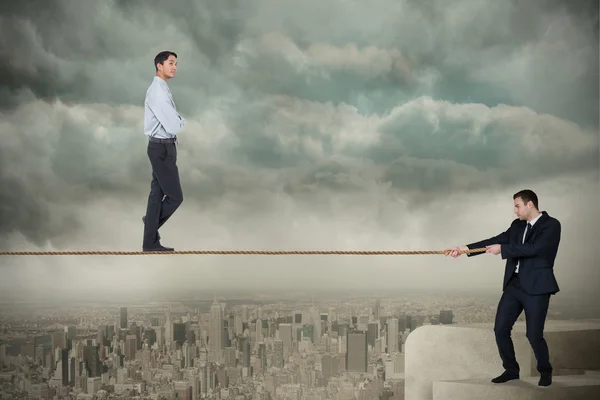 Young business man pulling a tightrope for businessman — Stock Photo, Image