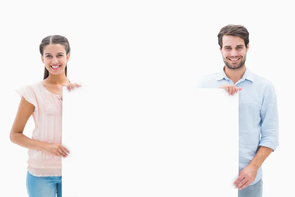 Attractive young couple smiling at camera holding poster — Stock Photo, Image