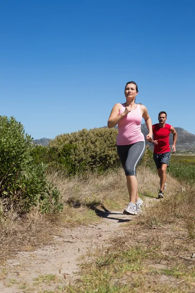 Pareja activa trotando en terreno rural — Foto de Stock