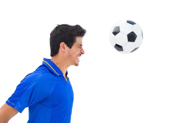 Jugador de fútbol en bola de encabezado azul — Foto de Stock