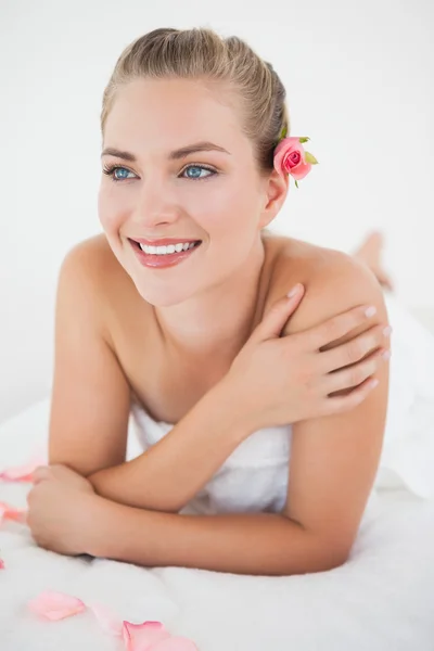 Bonita rubia tumbada sobre mesa de masaje con pétalos — Foto de Stock