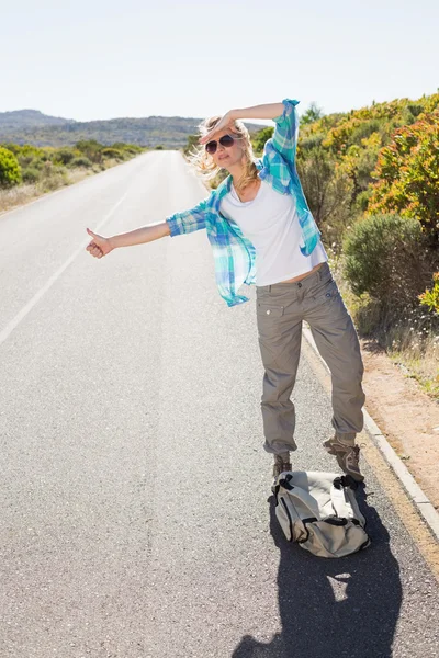 Blonde hitch hiking on rural road — Stock Photo, Image