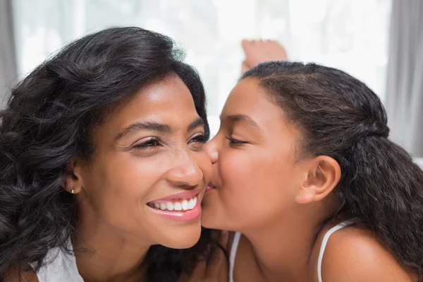 Bella donna sdraiata sul letto con sua figlia baciare guancia — Foto Stock