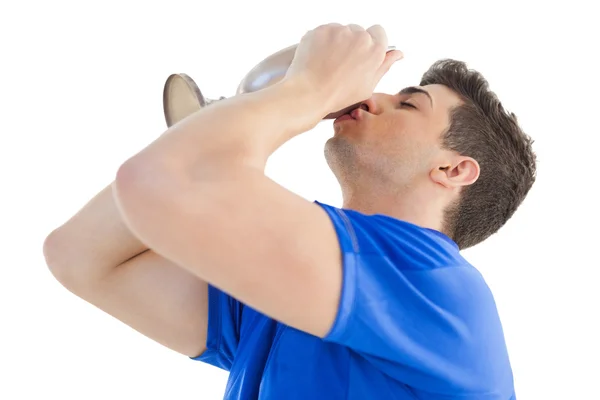 Fußballer im blauen Trikot küsst Siegerpokal — Stockfoto