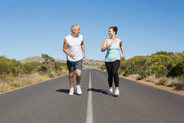 Fit couple running on the open road together — Stock Photo, Image