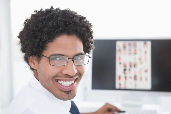 Joven editor sonriendo a la cámara en su escritorio —  Fotos de Stock