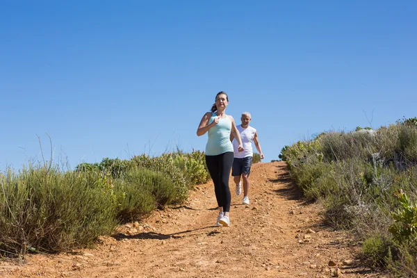 Fit couple running down mountain trail — Stock Photo, Image