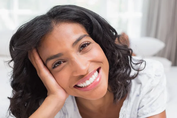 Mujer bonita acostada en la cama sonriendo a la cámara — Foto de Stock