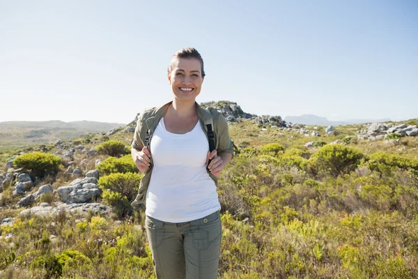 Bastante excursionista sonriendo a la cámara en terreno de montaña — Foto de Stock