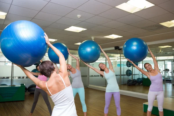 Fitness class holding up exercise balls in studio — Stock Photo, Image