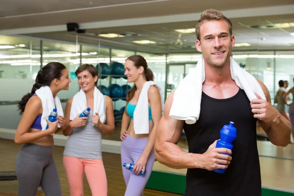 Fit man smiling at camera in busy fitness studio — Stock Photo, Image