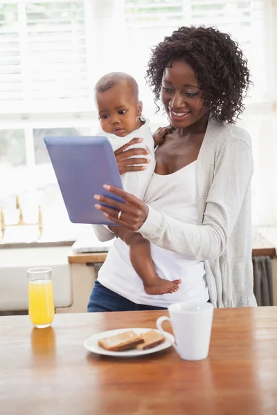 Feliz madre sosteniendo al bebé hijo mientras usa la tableta PC —  Fotos de Stock