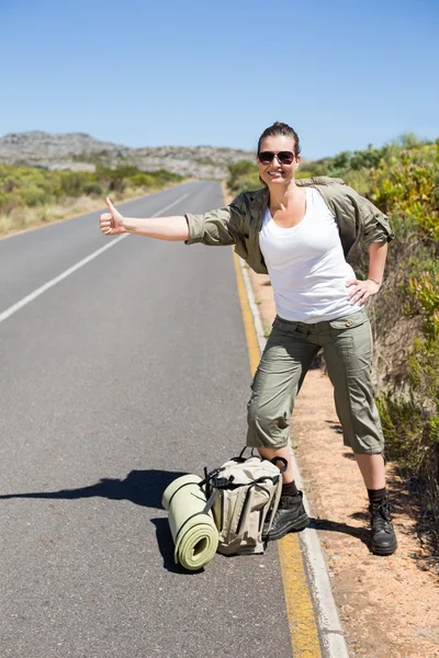 Pretty hitchhiker sticking thumb out on the road — Stock Photo, Image