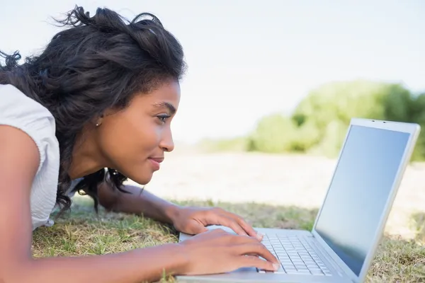 Příležitostné hezká žena ležící na trávě pomocí její laptop — Stock fotografie