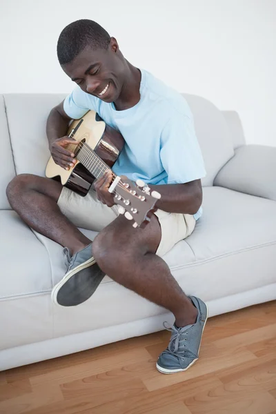 Casual man sitter på soffan spela gitarr — Stockfoto