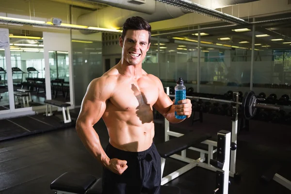 Gespierde man met energiedrank in gym — Stockfoto