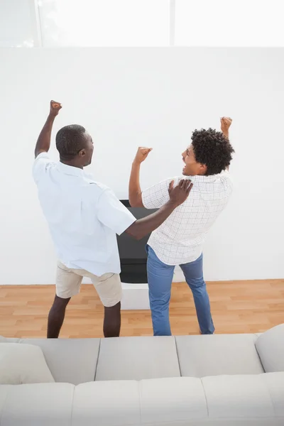 Fußballfans stehen und jubeln vor dem Fernseher — Stockfoto