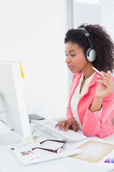 Casual photo editor working at desk listening to music — Stock Photo, Image