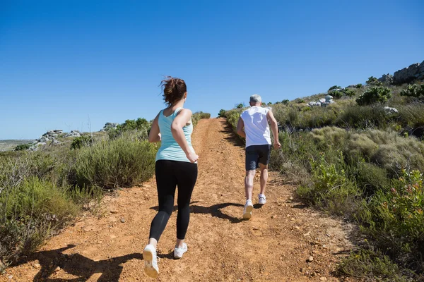 Fit couple jogging up mountain trail — Stock Photo, Image