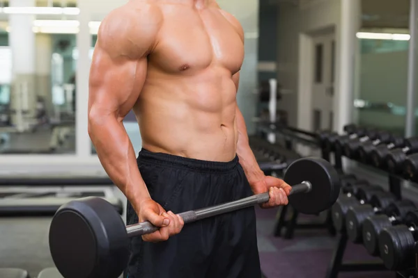 Mid section of shirtless muscular man lifting barbell — Stock Photo, Image