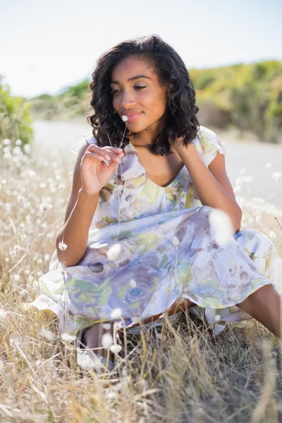 Glückliche hübsche Frau im floralen Kleid auf dem Gras sitzend — Stockfoto
