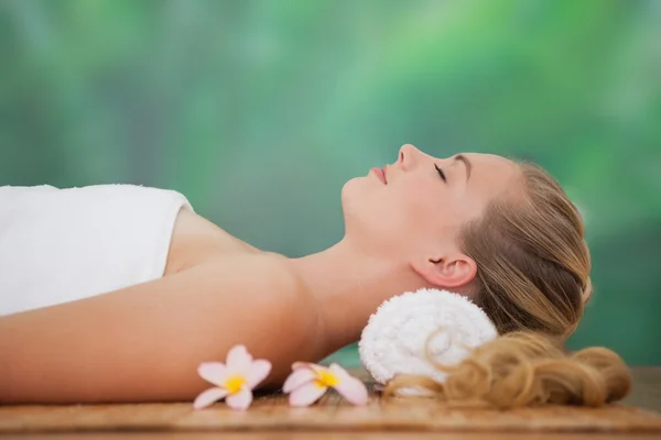 Tranquila rubia acostada sobre una alfombra de bambú con flores — Foto de Stock