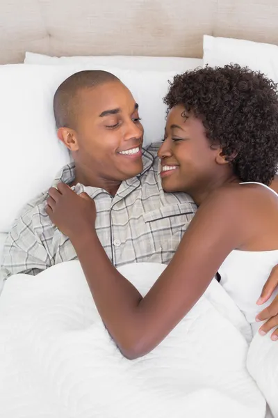 Casal feliz deitado na cama abraçando — Fotografia de Stock