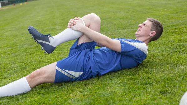 Football-speler in blauw gewonde liggend op de toonhoogte — Stockfoto