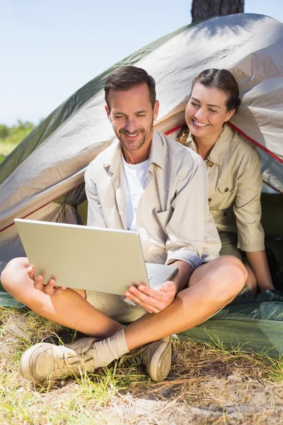 Coppia guardando il computer portatile fuori tenda — Foto Stock